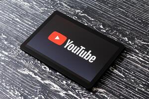 Tablet computer on a black wooden table with a social network YouTube logo on the screen. photo