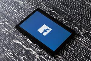 Tablet computer on a black wooden table with a social network facebook logo. photo