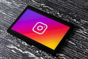 Tablet computer on a white wooden table with a social network instagram logo. photo