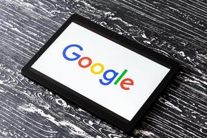 Tablet computer on a black wooden table with a search system google logo on the screen. photo