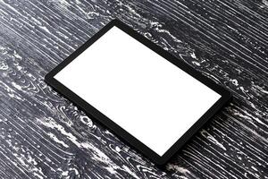 Black tablet with white screen on a wooden table. photo
