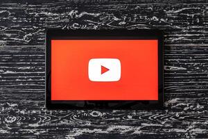 Tablet computer on a black wooden table with a social network YouTube logo on the screen. photo
