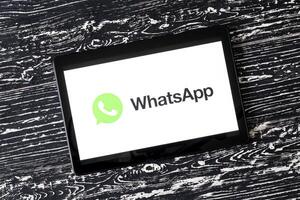 Tablet computer on a black wooden table with a messenger WhatsApp logo on the screen. photo
