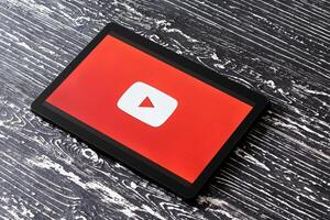 Tablet computer on a black wooden table with a social network YouTube logo on the screen. photo