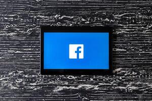 Tablet computer on a black wooden table with a social network facebook logo. photo