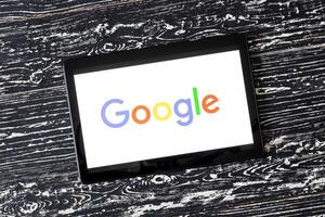 Tablet computer on a black wooden table with a search system google logo on the screen. photo