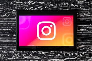 Tablet computer on a white wooden table with a social network instagram logo. photo