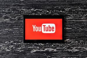 Tablet computer on a black wooden table with a social network YouTube logo on the screen. photo