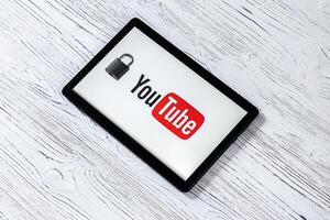 Black tablet computer on a white wooden table with a messenger youtube logo. photo