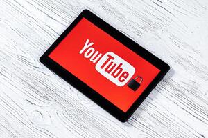 Black tablet computer on a white wooden table with a messenger youtube logo. photo