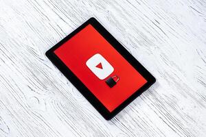 Black tablet computer on a white wooden table with a messenger youtube logo. photo