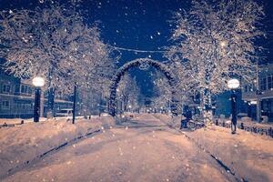 Winter night park with lanterns and Christmas decorations in snowfall. photo