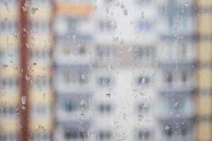 View through a rainy window on a blurred house. Bad rainy weather. photo