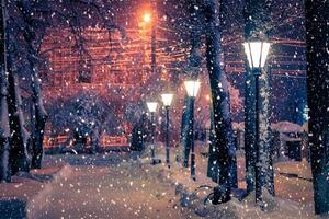 Winter night park with lanterns, pavement and trees covered with snow in snowfall. photo
