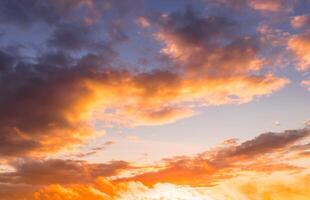 Colorful orange-purple dramatic clouds lit by the setting sun against the evening sunset sky. photo