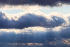 Sun rays breaking through cumulus clouds. The concept of divine light, a glimmer of hope or overcoming difficulties. Spiritual religious abstract backdrop. photo