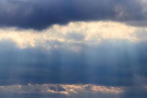 Sun rays breaking through cumulus clouds. The concept of divine light, a glimmer of hope or overcoming difficulties. Spiritual religious abstract backdrop. photo