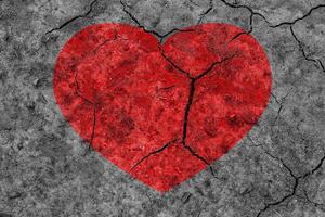 Red heart on a cracked texture. The concept of broken heart and the end of love. photo