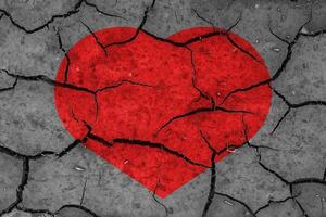 Red heart on a cracked texture. The concept of broken heart and the end of love. photo