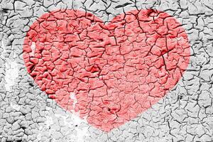 Red heart on a cracked texture. The concept of broken heart and the end of love. photo