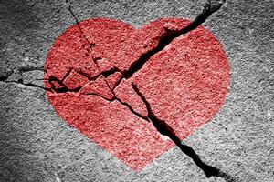 Red heart on a cracked texture. The concept of broken heart and the end of love. photo