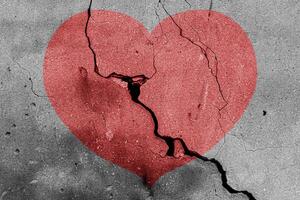 Red heart on a cracked texture. The concept of broken heart and the end of love. photo