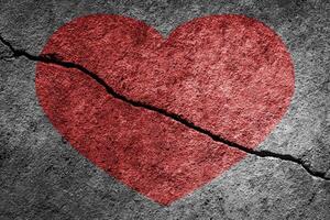 Red heart on a cracked texture. The concept of broken heart and the end of love. photo