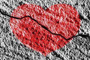 Red heart on a cracked texture. The concept of broken heart and the end of love. photo