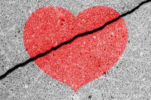 Red heart on a cracked texture. The concept of broken heart and the end of love. photo
