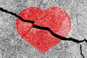 Red heart on a cracked texture. The concept of broken heart and the end of love. photo