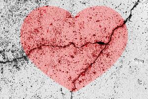 Red heart on a cracked texture. The concept of broken heart and the end of love. photo