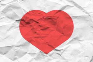 Red heart on a crumpled texture. The concept of broken heart and the end of love. photo
