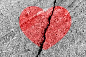 Red heart on a cracked texture. The concept of broken heart and the end of love. photo