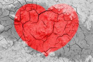 Red heart on a cracked texture. The concept of broken heart and the end of love. photo