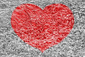 Red heart on a crumpled texture. The concept of broken heart and the end of love. photo