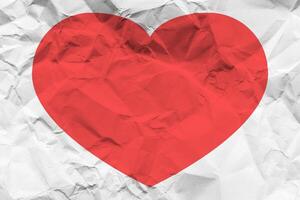 Red heart on a crumpled texture. The concept of broken heart and the end of love. photo
