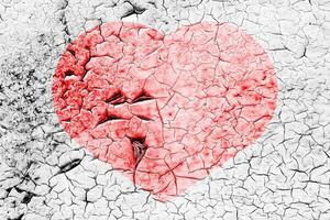 Red heart on a cracked texture. The concept of broken heart and the end of love. photo