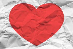 Red heart on a crumpled texture. The concept of broken heart and the end of love. photo