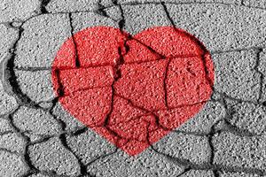 Red heart on a cracked texture. The concept of broken heart and the end of love. photo