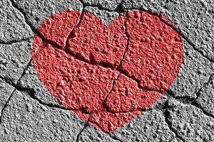 Red heart on a cracked texture. The concept of broken heart and the end of love. photo
