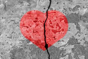 Red heart on a cracked texture. The concept of broken heart and the end of love. photo