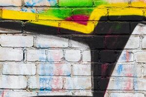 A fragment of colorful graffiti painted on a brick wall. Abstract backdrop for design. photo
