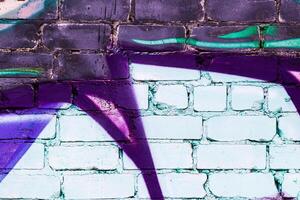 A fragment of colorful graffiti painted on a brick wall. Abstract backdrop for design. photo