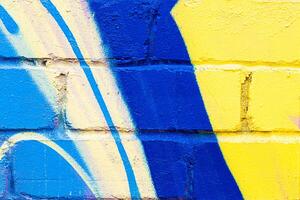 A fragment of colorful graffiti painted on a brick wall. Abstract backdrop for design. photo
