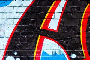 A fragment of colorful graffiti painted on a brick wall. Abstract backdrop for design. photo