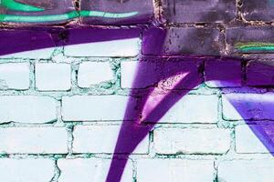 A fragment of colorful graffiti painted on a brick wall. Abstract backdrop for design. photo