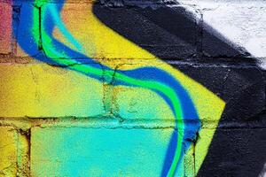 A fragment of colorful graffiti painted on a brick wall. Abstract backdrop for design. photo