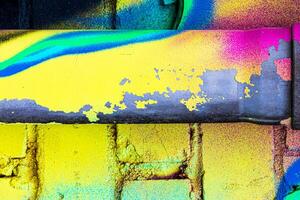 A fragment of colorful graffiti painted on a brick wall. Abstract backdrop for design. photo