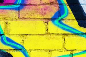 A fragment of colorful graffiti painted on a brick wall. Abstract backdrop for design. photo