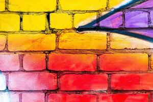 A fragment of colorful graffiti painted on a brick wall. Abstract backdrop for design. photo